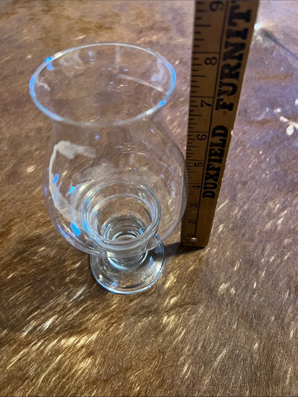 Clear glass hurricane candle holder features a pedestal base and a flared top